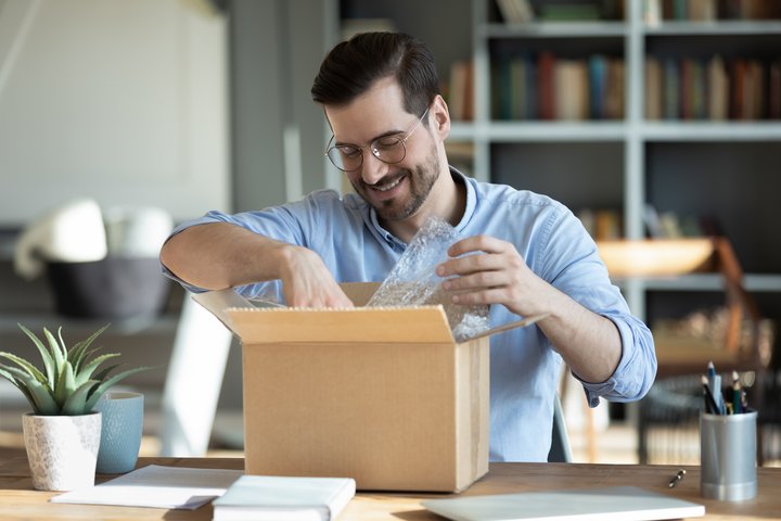 Smiling man with glasses opening box